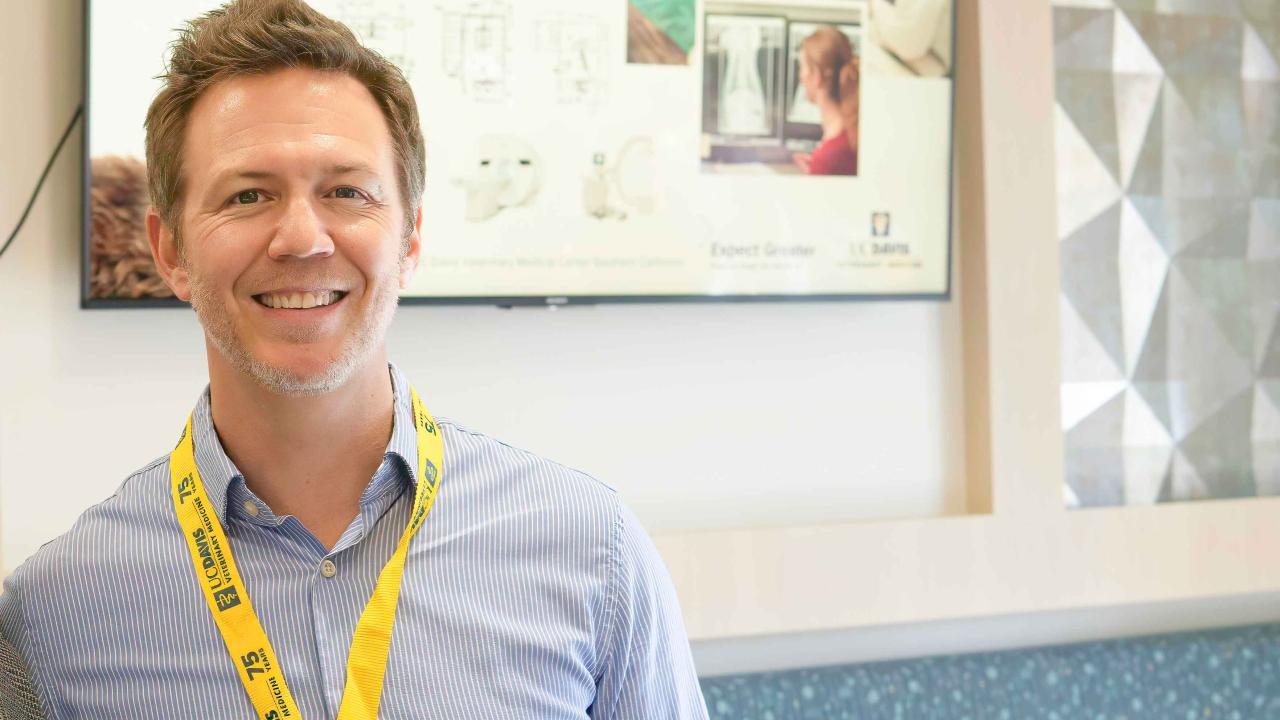 Picture of of veterinary cardiologist Dr. Timothy Hodge behind a wall with a poster.